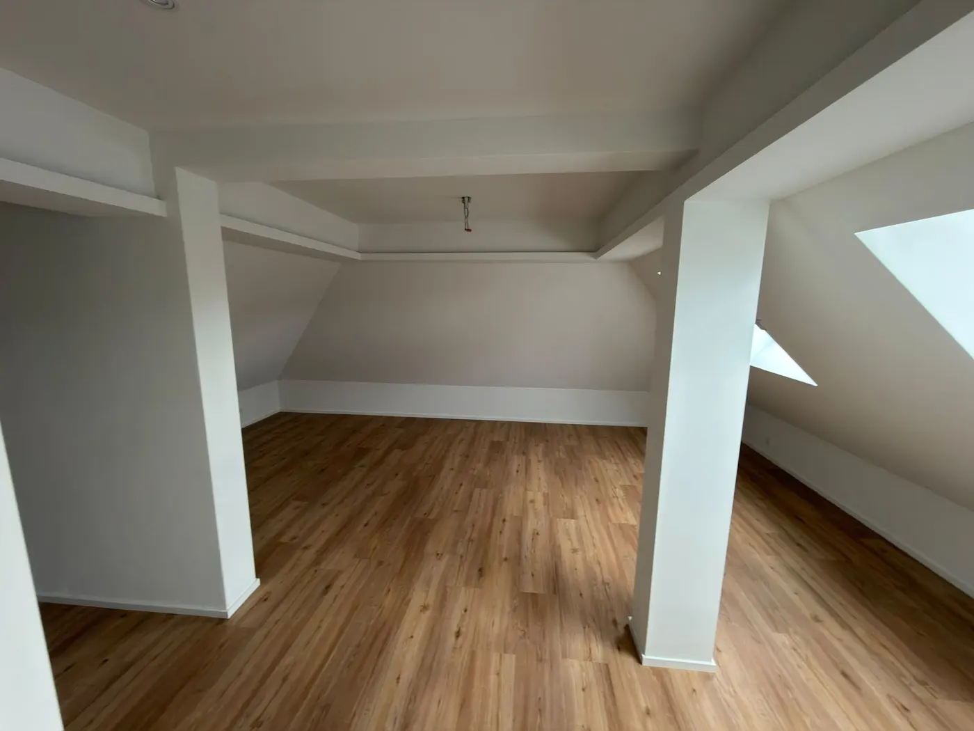 Fertig ausgebautes Dachgeschoss mit weissen Wänden und Holzboden