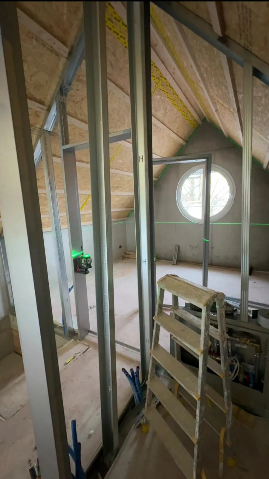 Metallständerwerk im Dachgeschoss mit Rundfenster und Linienlaser